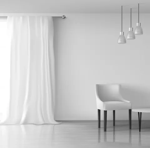Bright white room with a long curtain, pendant lamps and an armchair
